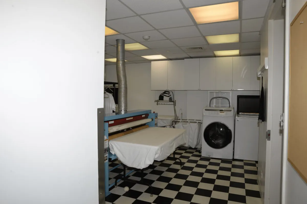 Laundry room with white wall cabinets, a front loading washer and a folding table