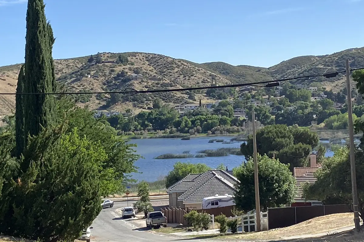 Hillside homes above a reservoir with mountains beyond in the Leona Valley area of Los Angeles County CA