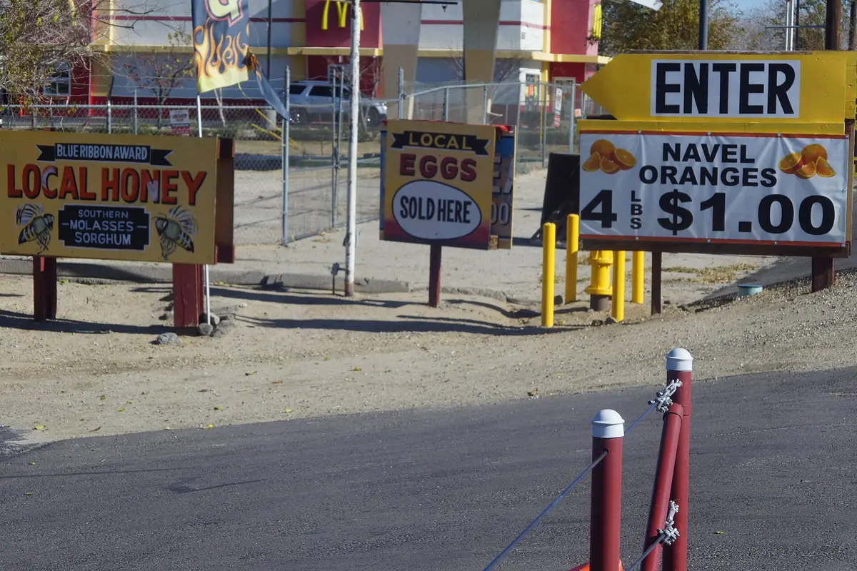 Roadside fruit stand with local honey and navel orange signs near Littlerock CA on Highway 138