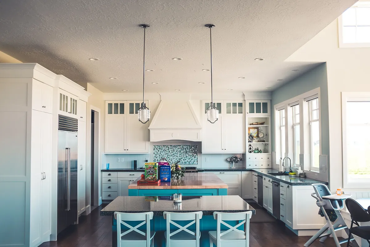 White shaker kitchen cabinets with an island and pendant lights in a Lancaster CA home